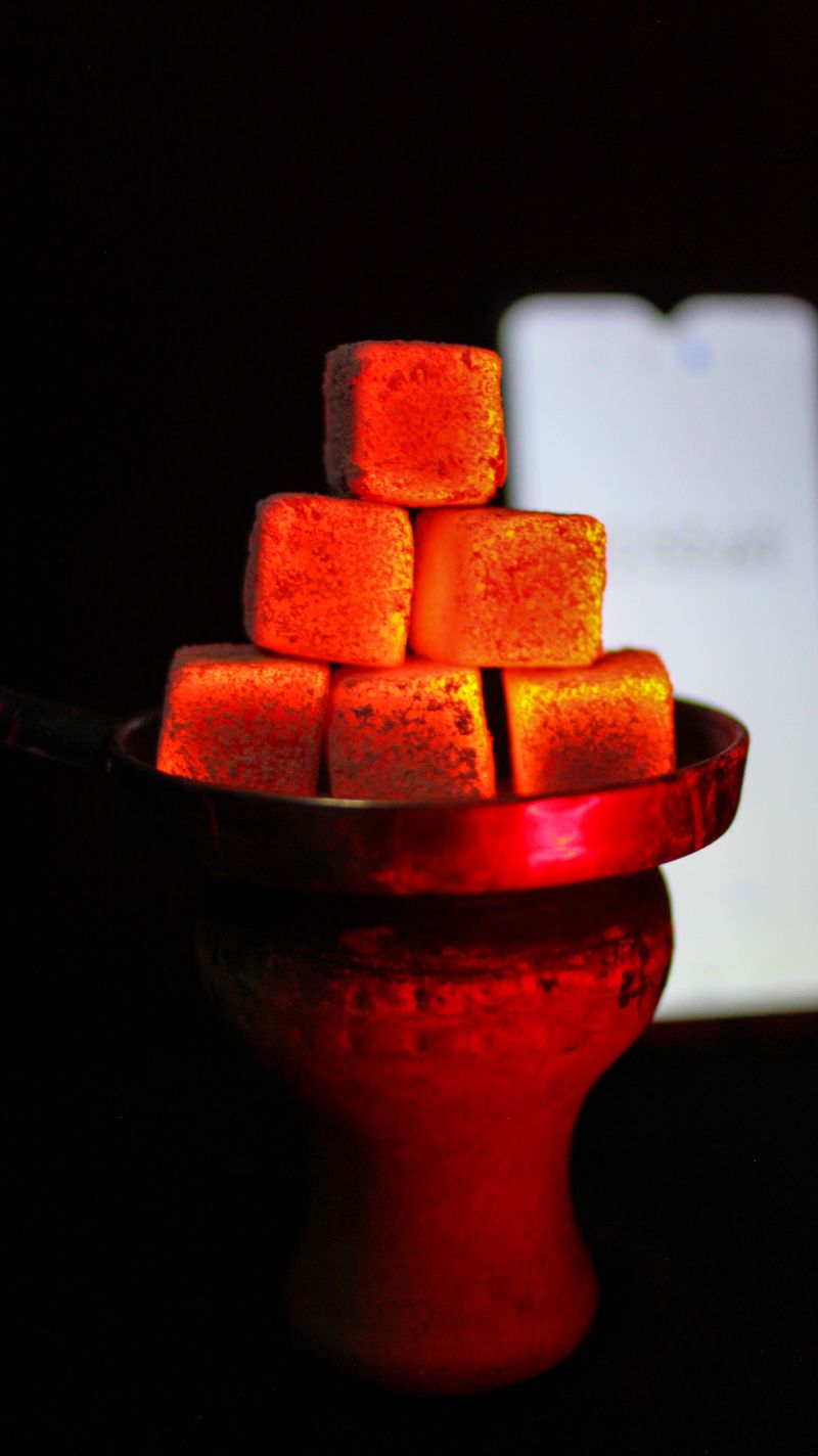 Sample glowing shisha charcoal cubes on a hookah bowl
